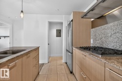 Kitchen featuring a gas range, stainless steel appliances, granite countertops, and wood-finish cabinetry - 