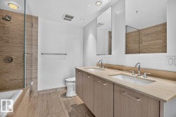 Bathroom featuring a dual vanity with undermount sinks, chrome fixtures, and a light wood-finish countertop - 