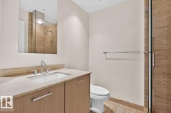 Contemporary bathroom featuring a wood-finish vanity with an integrated sink, stone countertop, and polished chrome fixtures - 