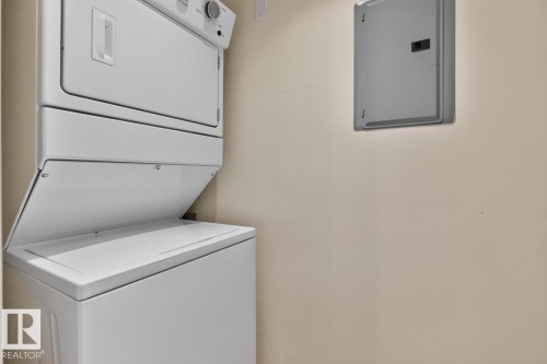 Dedicated laundry area featuring a white stacked washer and dryer unit - #407 2504 109 St Nw, Edmonton, AB - Indoor Photo Showing Laundry Room