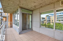 Private balcony featuring tiled flooring and a glass railing, providing access to the interior via a sliding glass door - 