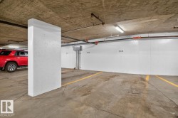 Dedicated parking space featuring concrete flooring, a painted concrete wall, and overhead fluorescent lighting - 