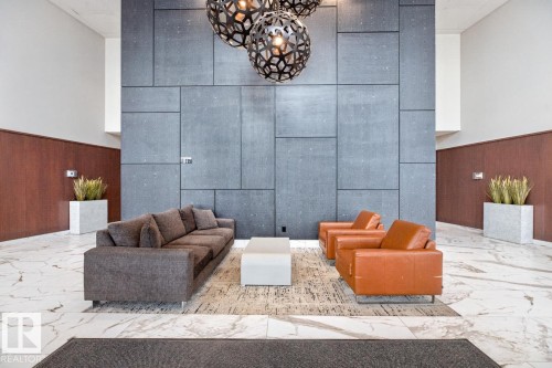 Lobby seating area featuring a large-format grey paneled accent wall - #407 2504 109 St Nw, Edmonton, AB - Indoor Photo Showing Other Room