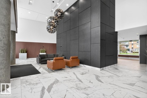Spacious lobby featuring polished marble-finish flooring and a striking dark paneled accent wall - #407 2504 109 St Nw, Edmonton, AB - Indoor Photo Showing Other Room