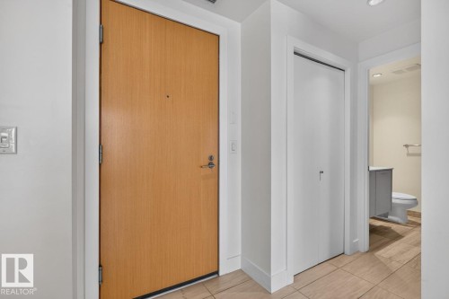 Entryway featuring a light wood-finish door, light-colored tile flooring, flush ceiling lighting, and a white bi-fold closet door - #407 2504 109 St Nw, Edmonton, AB - Indoor Photo Showing Other Room