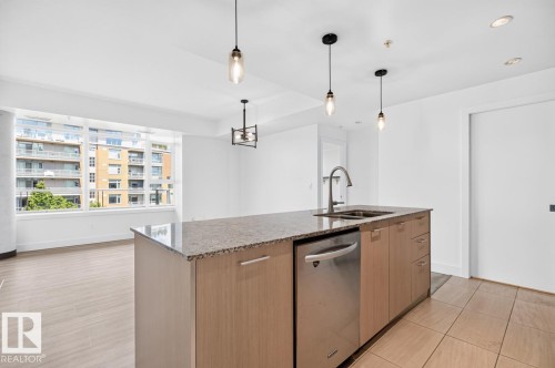 Kitchen island with granite countertop, integrated stainless steel sink, and stainless steel dishwasher - #407 2504 109 St Nw, Edmonton, AB - Indoor Photo Showing Kitchen With Double Sink With Upgraded Kitchen