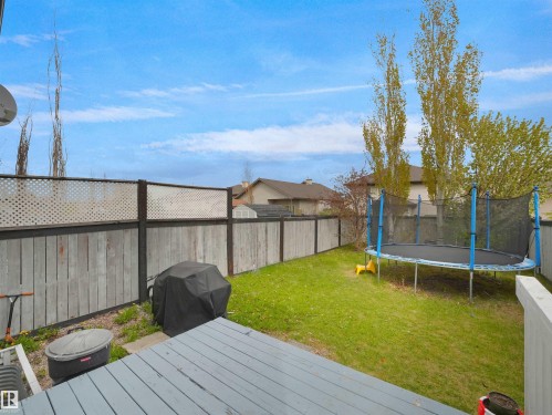 Expansive backyard featuring a gray painted deck, wood fencing with lattice accents, and a substantial green lawn - 16121 131A Street, Edmonton, AB - Outdoor With Deck Patio Veranda