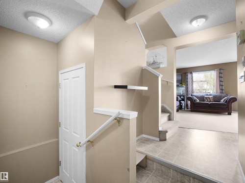 Multi-level entry foyer featuring tile flooring, neutral wall tones, and a staircase with a white railing - 16121 131A Street, Edmonton, AB - Indoor Photo Showing Other Room