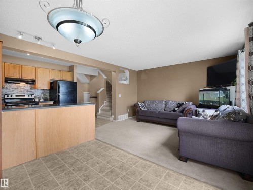 Open concept living area featuring a kitchen with light wood cabinetry, a mosaic tile backsplash, and a breakfast bar - 16121 131A Street, Edmonton, AB - Indoor Photo Showing Kitchen