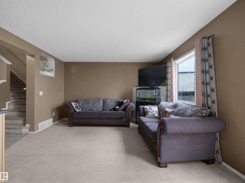 Living area featuring neutral-toned carpet and light brown wall paint - 16121 131A Street, Edmonton, AB - Indoor With Fireplace