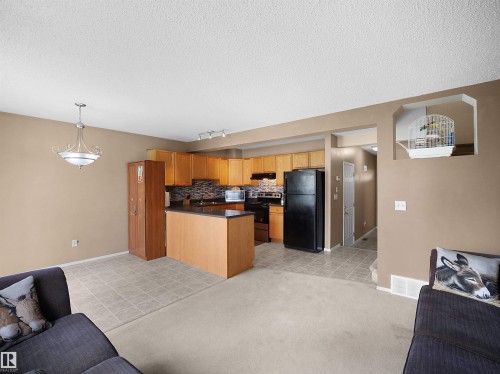 Open-concept living space featuring a kitchen with wood cabinetry, black appliances, and a dark countertop - 16121 131A Street, Edmonton, AB - Indoor Photo Showing Kitchen