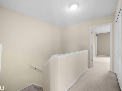 Interior hallway featuring light beige walls and neutral-toned carpeting - 16121 131A Street, Edmonton, AB - Indoor