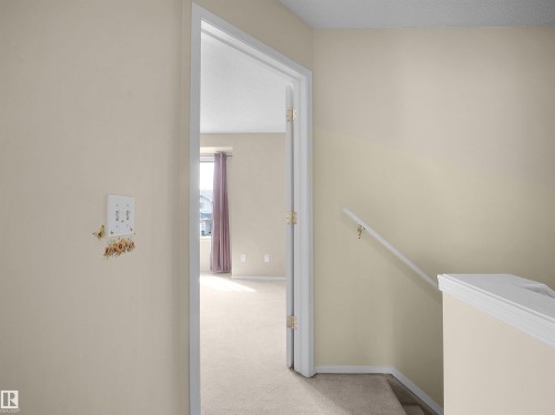 Light-colored walls and carpeting enhance the spacious feel of this interior hallway, featuring white trim and a white staircase handrail - 16121 131A Street, Edmonton, AB - Indoor Photo Showing Other Room
