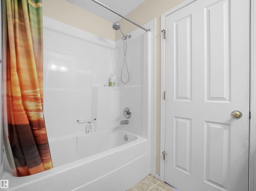 White bathtub and shower combination with a chrome shower head and fixtures - 16121 131A Street, Edmonton, AB - Indoor Photo Showing Bathroom