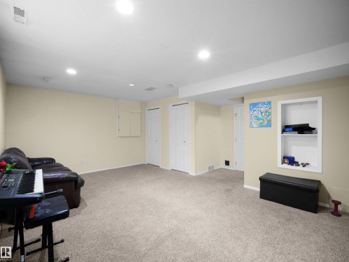 Spacious carpeted room featuring recessed lighting, a built-in shelving unit, and multiple white panel doors - 16121 131A Street, Edmonton, AB - Indoor Photo Showing Basement