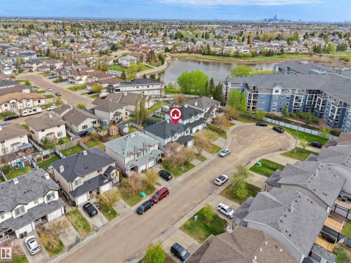 Residential neighborhood with a prominent lake, a large multi-story building, and a distant city skyline - 16121 131A Street, Edmonton, AB - Outdoor With Body Of Water With View