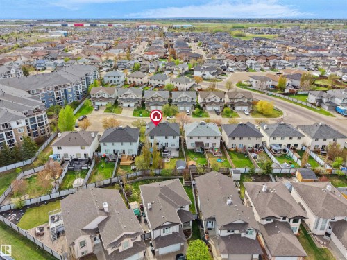 Aerial perspective showcasing a residential neighborhood with detached homes featuring shingled roofs and private backyards, alongside multi-story apartment buildings - 16121 131A Street, Edmonton, AB - Outdoor With View