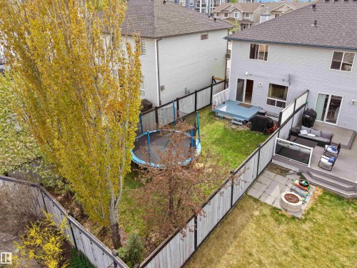 Fenced backyard featuring a multi-level deck, ground-level patio with a built-in fire pit, and mature trees - 16121 131A Street, Edmonton, AB - Outdoor With Exterior
