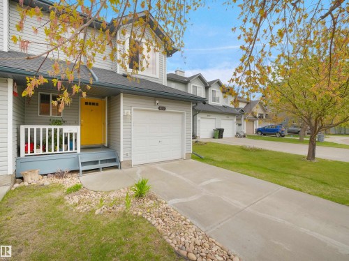 Contemporary townhome featuring light gray siding and a vibrant yellow entry door - 16121 131A Street, Edmonton, AB - Outdoor With Facade