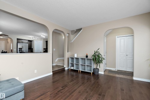 Spacious interior featuring dark wood-finish flooring, light neutral wall tones, and elegant arched doorways - 2007 74 Street, Edmonton, AB - Indoor