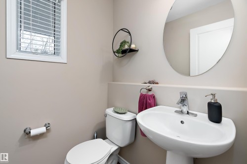 Modern bathroom featuring a pedestal sink, chrome faucet, and oval mirror - 2007 74 Street, Edmonton, AB - Indoor Photo Showing Bathroom