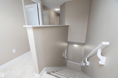 Carpeted staircase with white handrail and trim, featuring neutral wall tones and recessed lighting - 2007 74 Street, Edmonton, AB - Indoor Photo Showing Other Room
