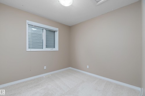 Neutral-toned room featuring a single window with blinds, light-colored carpeting, white baseboards, and a ceiling-mounted light fixture - 2007 74 Street, Edmonton, AB - Indoor Photo Showing Other Room
