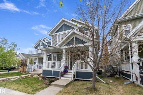 Two-story residential architecture featuring a covered front porch with white railings, grey siding, and a concrete walkway - 2007 74 Street, Edmonton, AB - Outdoor With Deck Patio Veranda