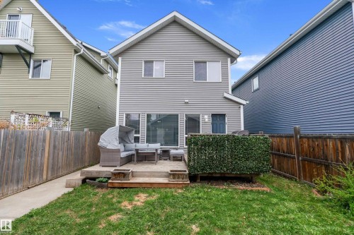 Rear exterior featuring gray siding, a second-story window, a lower-level window, and a door with a window pane - 2007 74 Street, Edmonton, AB - Outdoor With Deck Patio Veranda With Exterior