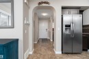 Arched doorway entry featuring stone-look flooring, white baseboards, and a white paneled door - 2007 74 Street, Edmonton, AB  - Indoor Photo Showing Other Room 
