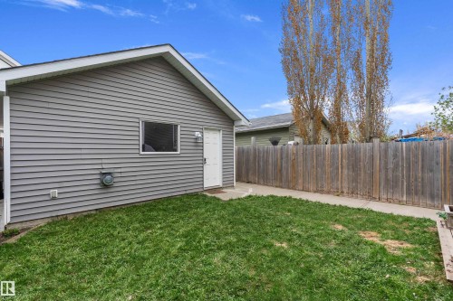 Rear exterior featuring gray horizontal siding, white trim, a side entry door, and a window - 2007 74 Street, Edmonton, AB - Outdoor