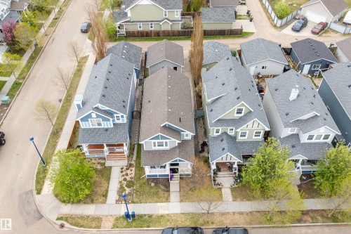 Modern residential streetscape featuring a blue two-story home with a front porch, dormer windows, and a gray shingled roof - 2007 74 Street, Edmonton, AB - Outdoor With View