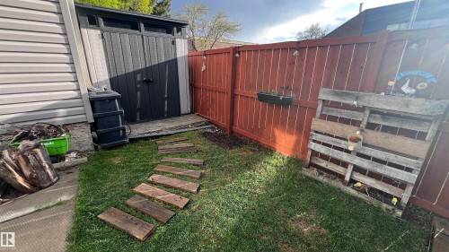 Fenced backyard area featuring a storage shed, wood-plank pathway, and a privacy fence - 5642 148 Street, Edmonton, AB - Outdoor With Exterior