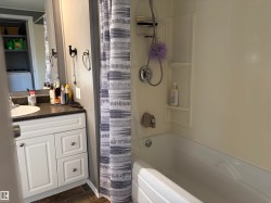 Bathroom featuring a single vanity with white cabinetry, dark countertop, and integrated sink - 