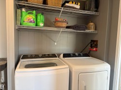 Laundry closet featuring a washer and dryer, painted paneling, and wire shelving - 