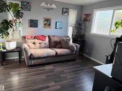Bright room featuring light grey walls, wood-finish flooring, white window trim, and a white baseboard - 
