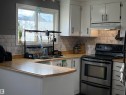 Kitchen featuring light wood-finish countertops, subway tile backsplash, white cabinetry with black hardware, and a stainless steel electric range - 4108 49 Avenue, Bonnyville Town, AB  - Indoor Photo Showing Kitchen With Double Sink 