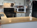 Kitchen featuring wood-finish countertops, white cabinetry with black hardware, and a stainless steel oven - 4108 49 Avenue, Bonnyville Town, AB  - Indoor Photo Showing Kitchen With Double Sink 