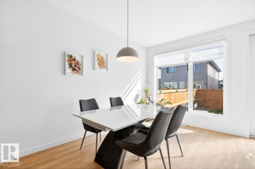 Bright interior space featuring a large window, a modern pendant light fixture, and wood-finish flooring - 17347 100 Street, Edmonton, AB - Indoor Photo Showing Dining Room
