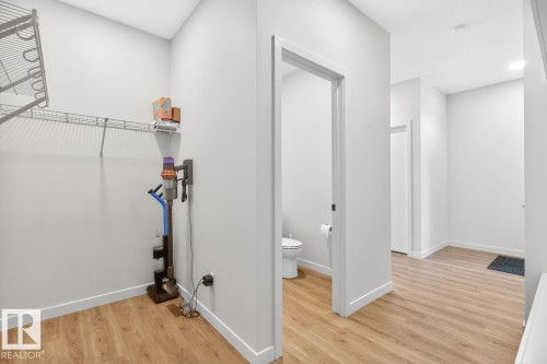 Corridor featuring wood-finish flooring, white baseboards, and a clear doorway to a bathroom with a white toilet - 17347 100 Street, Edmonton, AB - Indoor Photo Showing Other Room