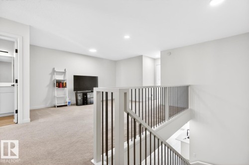 Upper-level landing featuring neutral carpeting, recessed lighting, and a contemporary stair railing with black balusters - 17347 100 Street, Edmonton, AB - Indoor Photo Showing Other Room