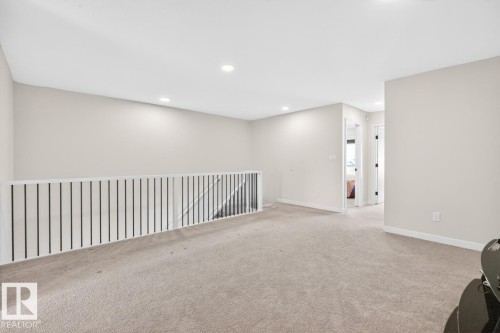 Upper-level landing featuring neutral carpeting, recessed ceiling lighting, and a white railing with dark vertical balusters - 17347 100 Street, Edmonton, AB - Indoor Photo Showing Other Room