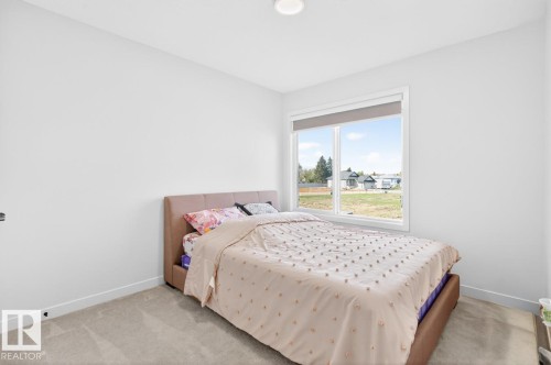 Bright interior space featuring a large window with white trim, neutral carpet flooring, and white walls - 17347 100 Street, Edmonton, AB - Indoor Photo Showing Bedroom