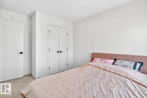 Carpeted room featuring white walls, a built-in closet with double doors, and a single entry door, all with matte black hardware - 17347 100 Street, Edmonton, AB - Indoor Photo Showing Bedroom