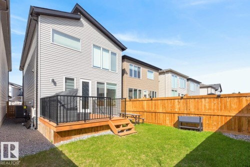 Expansive backyard featuring a manicured lawn, full wood fencing, and a built-in wood deck with black metal railing - 17347 100 Street, Edmonton, AB - Outdoor With Deck Patio Veranda