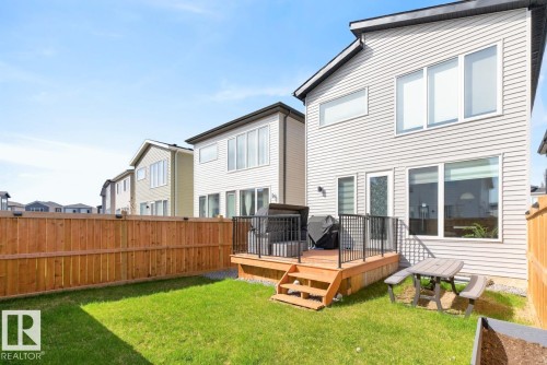 Expansive rear yard featuring a wooden deck with black metal railings, a full-height privacy fence, and a vibrant green lawn - 17347 100 Street, Edmonton, AB - Outdoor