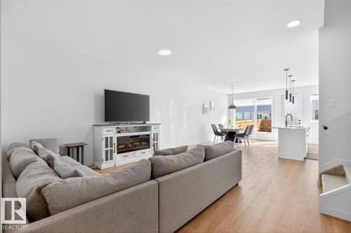 Open-concept living space featuring wood-finish flooring, recessed lighting, and a modern built-in electric fireplace entertainment unit - 17347 100 Street, Edmonton, AB - Indoor Photo Showing Living Room