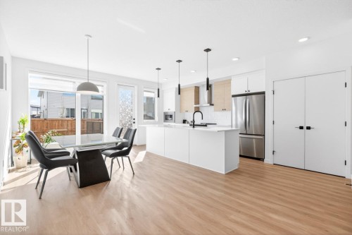 Open-concept living space featuring wood-finish flooring, recessed lighting, and a white kitchen island with pendant lighting - 17347 100 Street, Edmonton, AB - Indoor