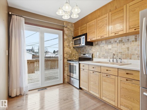 Kitchen featuring light wood-finish cabinetry, a stone tile backsplash, and light wood-finish flooring - 13504 116 St Nw, Edmonton, AB - Indoor Photo Showing Kitchen
