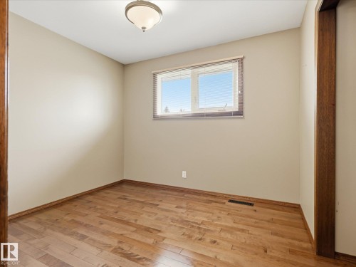 Room featuring wood-finish flooring, a double window with blinds, and neutral painted walls - 13504 116 St Nw, Edmonton, AB - Indoor Photo Showing Other Room